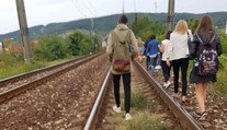 Železniciam sa pokazil vlak. Cestujúci z neho vystúpili a po koľajniciach kráčali na stanicu
