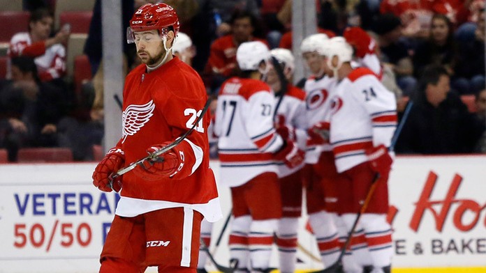 Útočník Detroitu Tomáš Tatar smutne korčuľuje okolo hráčov Caroliny, ktorí oslavujú gól.