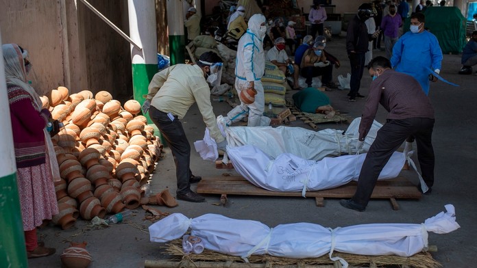 Ľudia zoraďujú telá obetí COVID-19 v krematóriu v indickej metropole Naí Dillí.
