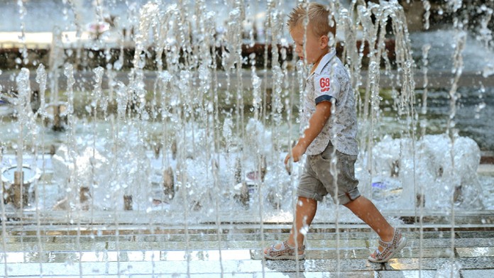 Chlapec sa ochladzuje pri fontáne počas horúceho dňa v Košiciach.