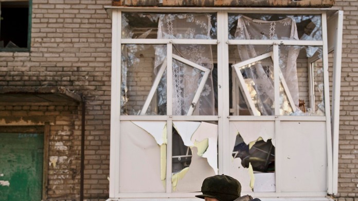 Žena prechádza okolo  ostreľovaním zničeného obytného domu vo výchoukrajinskom meste Debaľceve.