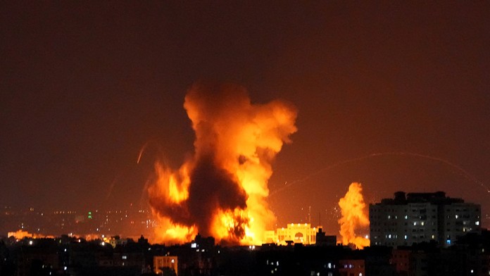 Na snímke dym a plamene stúpajú z budovy zasiahnutej raketami vystrelenými palestínskymi militantmi na Izrael.