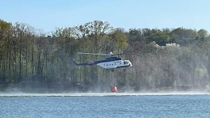Hasičský vrtuľník naberá vodu do bambi vaku.