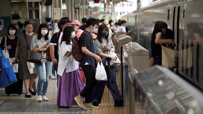 Cestujúci s ochrannými rúškami nastupujú do vlaku na železničnej stanici v Tokiu.
