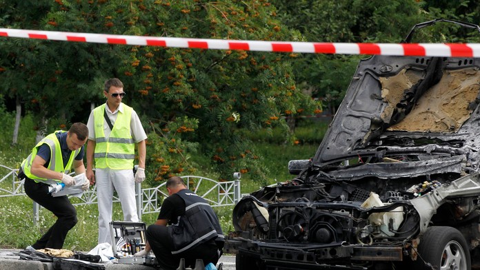 Forenzní experti prehľadávajú vrak automobilu.