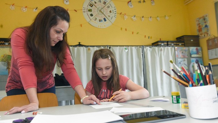 Asistentka učiteľa pomáha žiačke s úlohami a učivom v škole v Budapešti..jpg