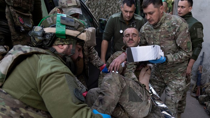 Zdravotníci prenášajú svojho zraneného spolubojovníka na nosidlách pri meste Bachmut.