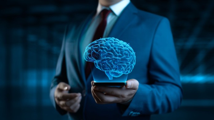 Obrázok holografického mozgu vznášajúceho sa nad telefónom pred postavou muža, ktorý telefon drží