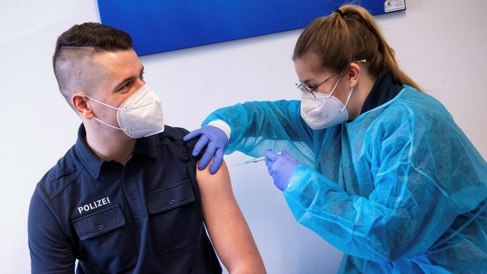 Zdravotníčka podáva vakcínu proti ochoreniu COVID-19 od spoločnosti AstraZeneca policajtovi.