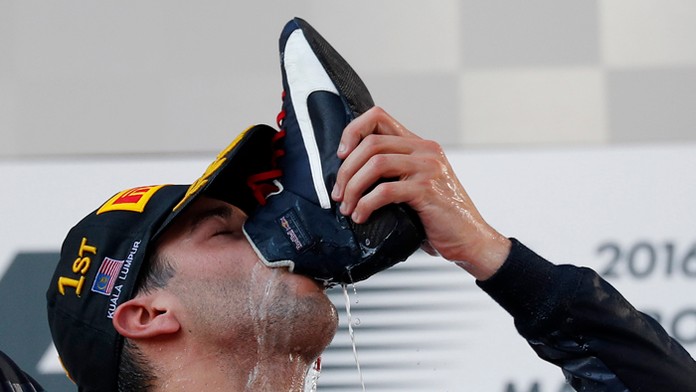 Daniel Ricciardo pije šampanské z topánky počas oslavy víťazstva vo VC Malajzie.