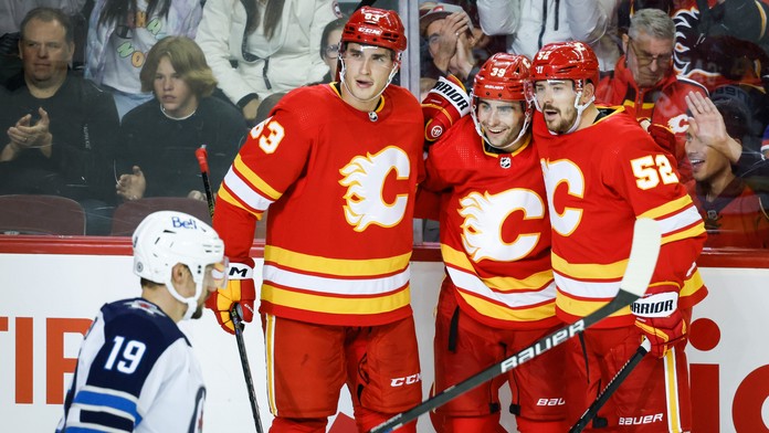 Hokejista Calgary Flames Matthew Coronato (39) sa teší z gólu so spoluhráčomi Adamom Ružičkom (63).