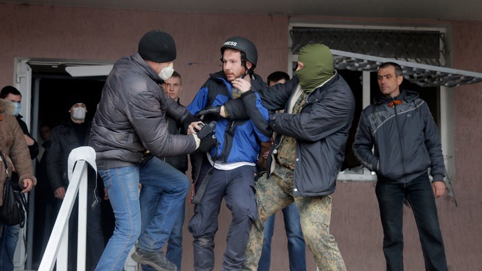 Maskovaní proruskí aktivisti útočia na britského fotografa Fredericka Paxtona počas útoku na policajnú stanicu v ukrajinskom mes