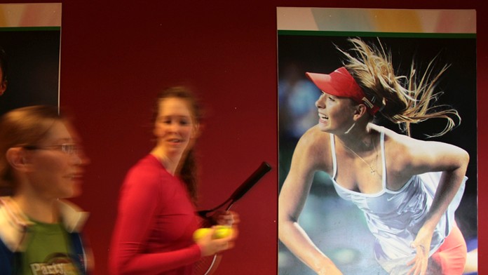 Študentky tenisovej akadémie kráčajú okolo plagátu s podobizňou ruskej tenistky Marie Šarapovovej v Kazani.