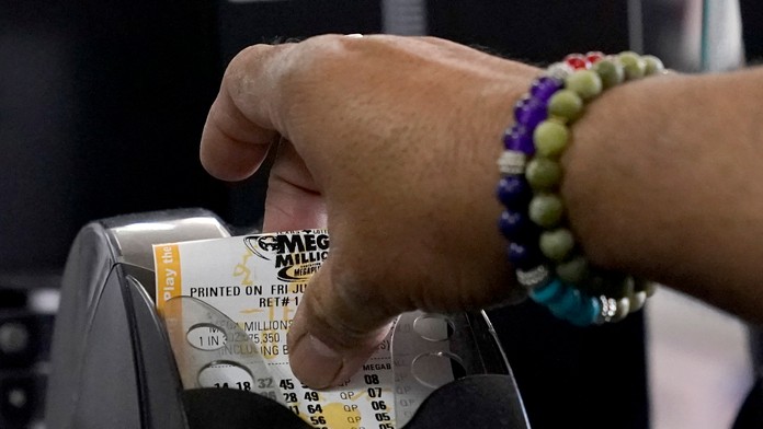 Zamestnanec samoobsluhy vyťahuje zákazníkovi tiket americkej lotérie Mega Millions v texaskom Richardsone.