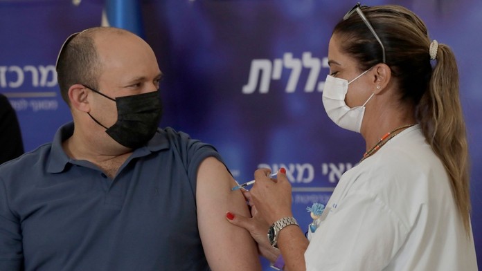 Izraelský premiér Naftali Bennett dostáva posilňovaciu dávku vakcínu proti ochoreniu COVID-19 v nemocnici v meste Kfar Saba.
