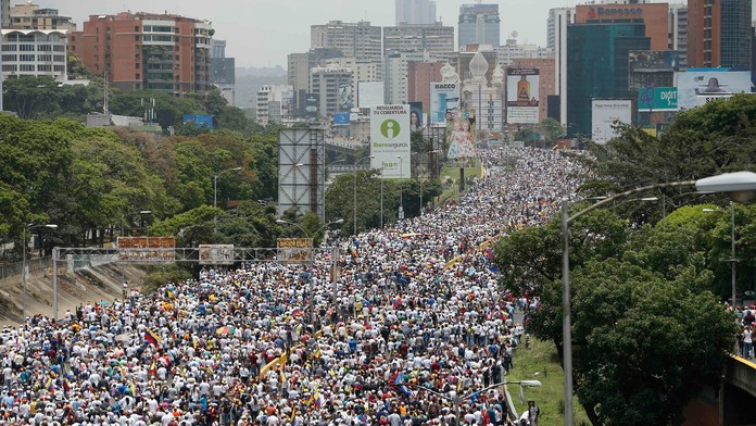 Protivládni demonštranti pochodujú po diaľnici počas masovej demonštrácie v Caracase.