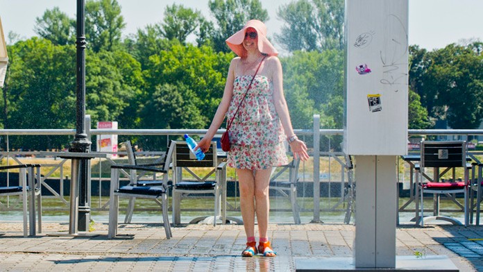 Na snímke dievča sa ochadzuje vodou, ktorá strieka z deravej hadice v Bratislave.