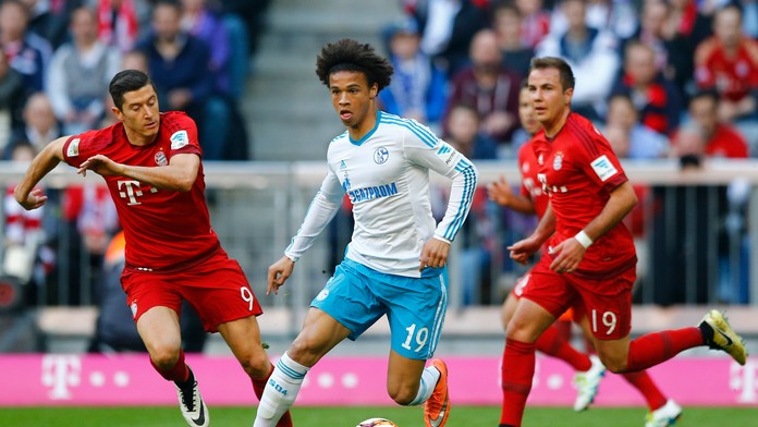 Hráč Schalke Leroy Sane v súboji o loptu s hráčmi Bayernu Robertom Lewandowskim a Máriom Götzem.