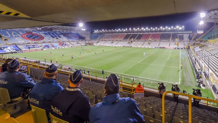Policajti sedia na prázdnom štadióne počas zápasu D-skupiny EL UEFA medzi FC Bruggy a SSC Neapol.