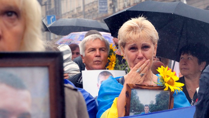Ľudia držia fotografie svojich príbuzných, ktorí ako vojaci zahynuli počas konfliktu so separatistami.
