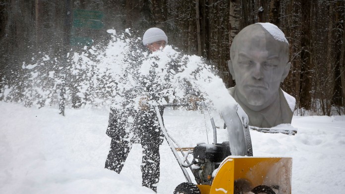 Muž s frézou odpratáva sneh pred sochou bývalého sovietskeho vodcu V. I. Lenina v lese na okraji Petrohradu