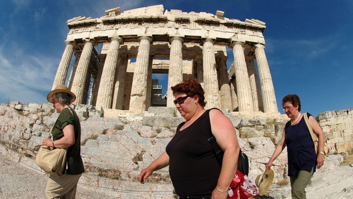 Turisti prechádzajú popred chrám Partenón na aténskej Akropole.