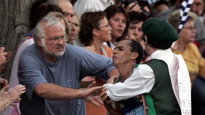 Muž v kostýme napáda brazílskeho atléta Vanderleia De Limu, na poslednom úseku maratónskej trate v Aténach.