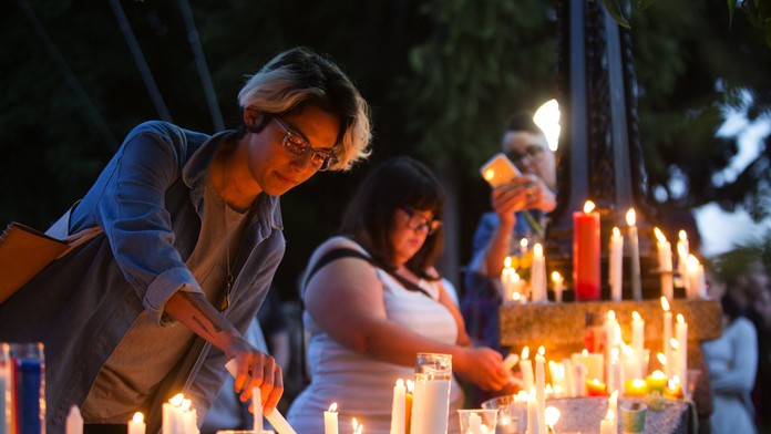 Ľudia zapaľujú sviečky počas spomienkového zhromaždenia pre obete masovej streľby.jpg