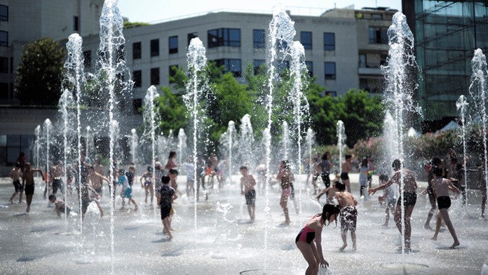 Deti sa hrajú vo fontáne počas slnečného a teplého počasia v parku v Paríži.