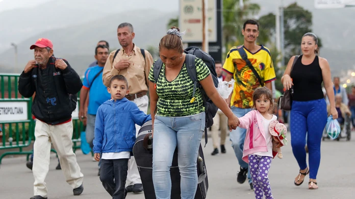 Venezuelská migrantka Yelitza Fuenmayorová s kufrom a deťmi kráča cez most do severokolumbijského mesta Cúcuta.