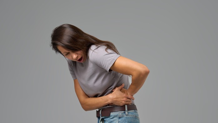 Žena sa chytá za bok a sťažuje sa na bolesti.