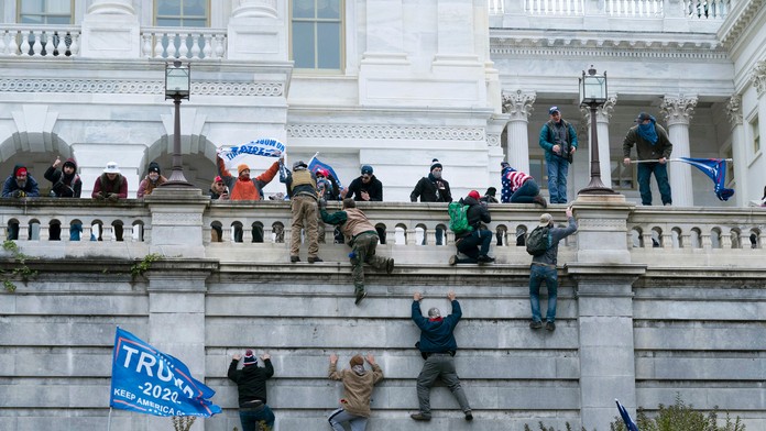 Na snímke stúpenci amerického prezidenta Donalda Trumpa sa vešajú na budovu Kapitolu vo Washingtone.