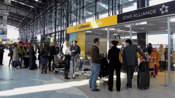 Cestujúci čakajú v hale pražského medzinárodného letiska Ruzyň.