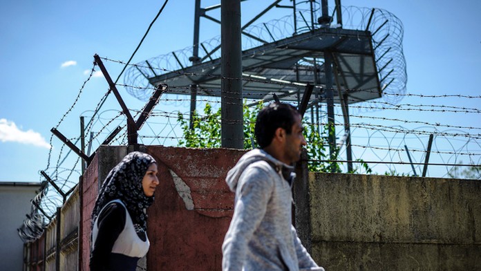 Nelegálni migranti kráčajú okolo plotu utečeneckého tábora v Debrecíne.