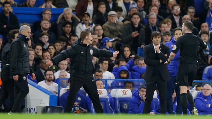 Rozhodca Michael Oliver upokojuje situáciu medzi lavičkami súperov.