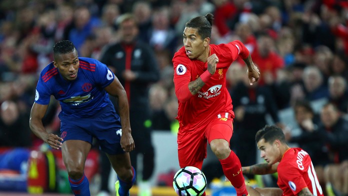 Hráč Liverpoolu Roberto Firmino a vľavo hráč United Eric Bailly.