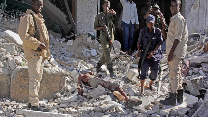 Členovia bezpečnostných jednotiek stoja vedľa mŕtveho tela po bombovom útoku na hotel Ambassador