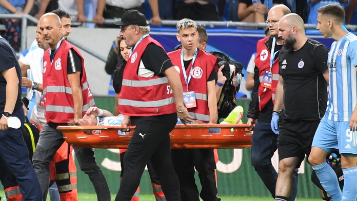 Futbalista Slovana Jurij Medveděv leží na nosidlách počas proti Ferencvárosu. 