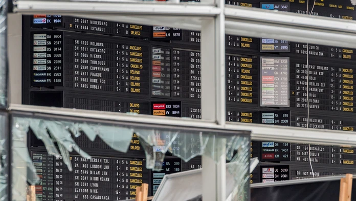 Pohľad cez rozbité okno na tabuľu odletov po teroristickom výbuchu na letisku Zaventem 23. marca.