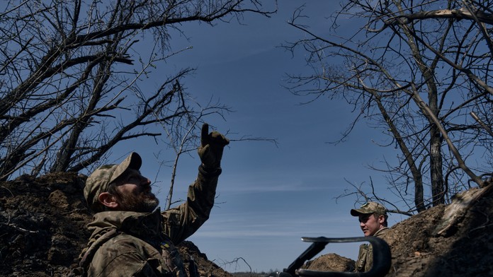 Ukrajinský vojak ukazuje na ruský dron zo zákopu na frontovej línii v Bachmute.