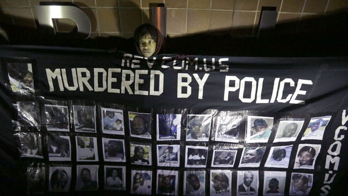Asmera Smithová drží plagát s fotografiami ľudí, ktorí údajne zomreli po záasahu polície.