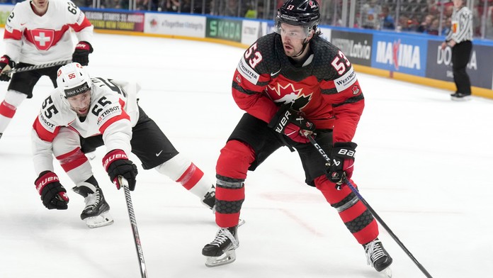 Švajčiarsky hráč Romain Löffel (vľavo) bojuje o puk s Kanaďanom Michaelom Carconem.