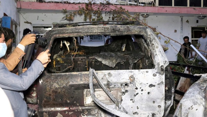 Afganskí novinári si fotia zničené auto v dome po útoku americkej armády dronom na teroristickú organizáciu Islamský štát v Kábu
