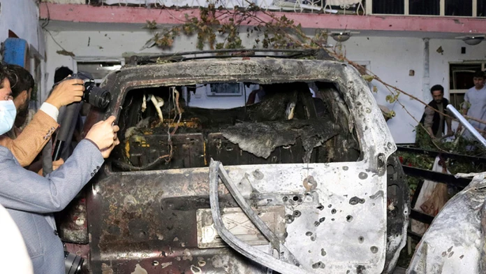 Afganskí novinári si fotia zničené auto v dome po útoku americkej armády dronom na teroristickú organizáciu Islamský štát v Kábu