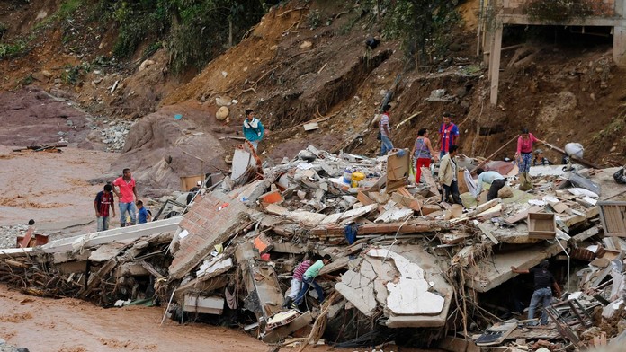 Ľudia kráčajú po ruinách zrútenej budovy v kolumbijskom meste Mocoa.
