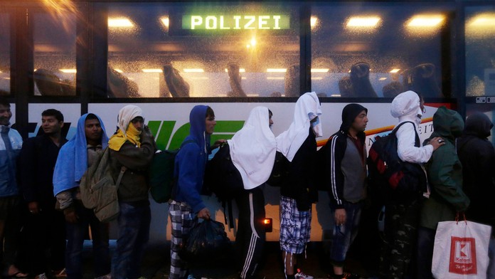Migranti v rade pred policajným autobusom na maďarsko-rakúskej hranici.