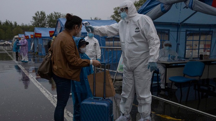 Zamestnanec meria telesnú teplotu cestujúcej z čínskeho mesta Wu-chan.