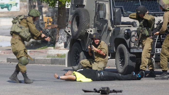  Izraelský vojak strieľa na palestínskeho útočníka v žltej novinárskej veste, ktorý zaútočil na iného vojaka nožom a zranil ho. 