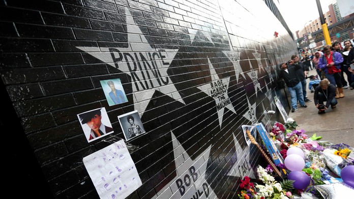 Fanúšikovia pri kvetoch, sviečkach a fotografiách na múre hviezd na First Avenue v americkom Minneapolise