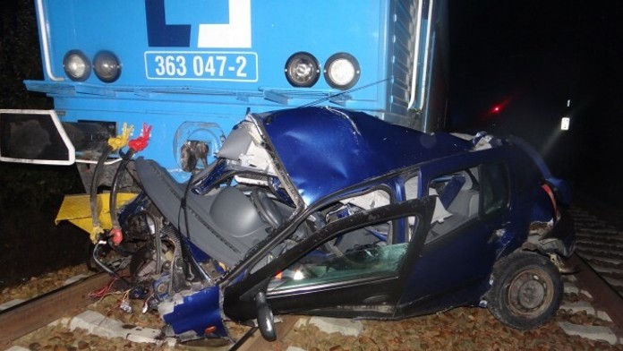 Zošrotované auto vlakom na trati v obci Kařízek na Rokycansku.